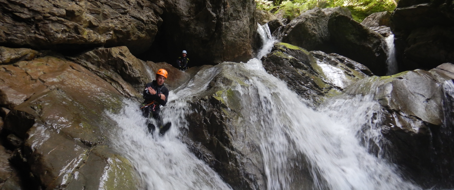 CanyoningEinsteiger MannrutschtfröhlichüberSteineimCanyon