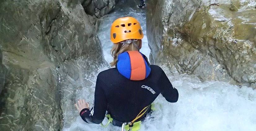 Eine Frau die im Wasser rutscht und das Canyoning richtig geniesst