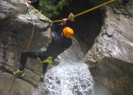 Ein Mann beim Canyoning, der mit Seil Hindernisse überwindet